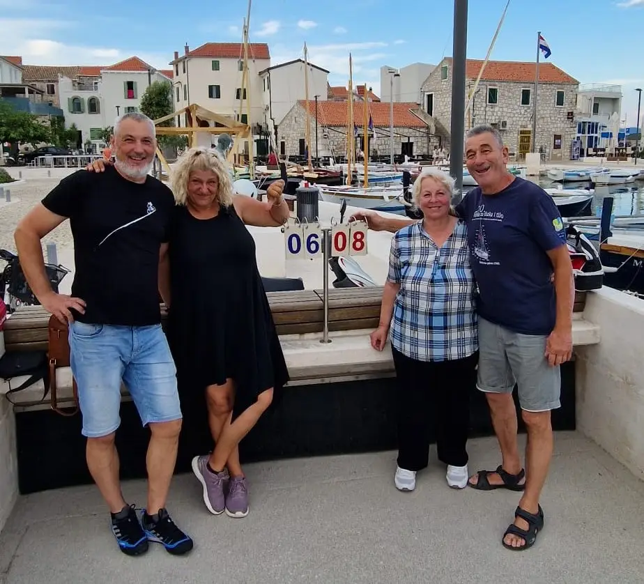 Na slici su domaćini An-Mar apartmana zajedno s mještanima tijekom tradicionalnog turnira u bućanju u Betini. Bućanje je omiljena lokalna igra s loptama koja se igra na zogu – posebno pripremljenom, ravnom terenu od pijeska. Ljeti gotovo svako veče mještani se okupljaju za igru, a lokalni ženski, muški i turniri parova održavaju se tijekom srpnja, kolovoza i rujna. Fotografija dočarava prijateljsku i zajedničku atmosferu kojom se ponose stanovnici Betine.