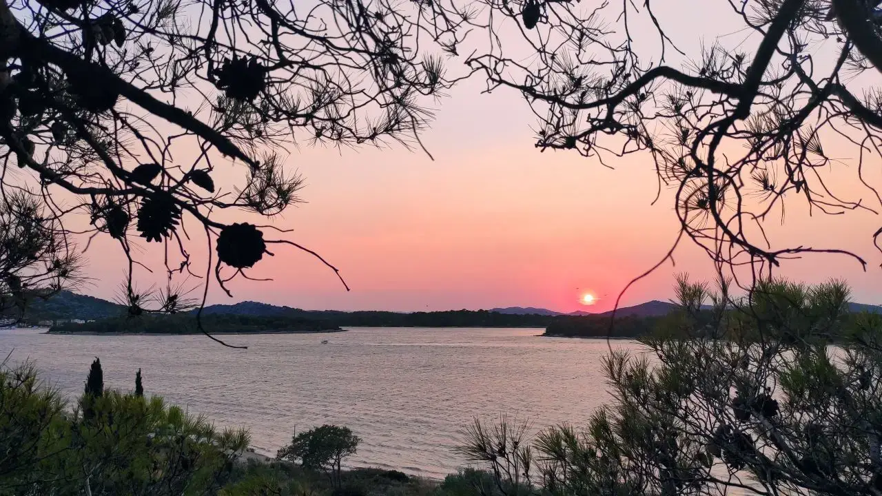 Naslovna 8 Slika prikazuje zalazak sunca snimljen iz borove šumice na južnoj strani poluotoka Gradina, na otoku Murteru, iza kuće u kojoj su smješteni An-Mar apartmani. U kadru se pruža pogled na more i obližnje otočiće. Ova lokacija, u blizini arheološkog nalazišta Colentum, odiše mirom, prirodnom ljepotom i autentičnim mediteranskim ugođajem.